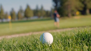 Yeşil sahadaki beyaz golf topu fotokopi uzayı ile aydınlık bir günde bulanık golf sahasında çekilecek. Spor, eğlence sektörü. Golf topu ve golf sopası yeşil çimlerin üzerinde.