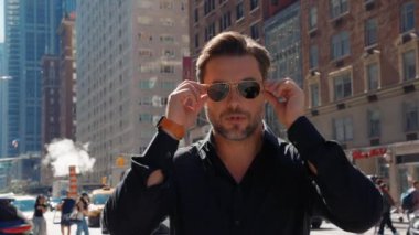 Kendine güvenen şık bir adam New York sokaklarındaki kameraya bakıyor. New York 'ta sokakta yürüyen bir iş adamı. New York 'ta Times Meydanı yakınlarındaki 5. Cadde' de bir erkek..