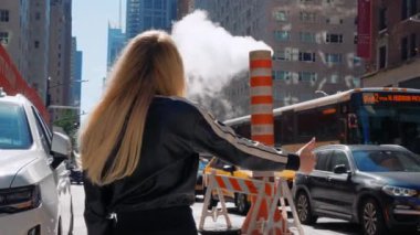New York, Manhattan 'da 5. caddede taksiye yetişmeye çalışan genç bir kadın. New York 'lu iş kadını taksiye yetişmek için acele ediyor. İş kadını şehirde cep telefonuyla taksiye biniyor.