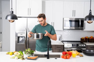 Profesyonel üniformalı modern şef. Kaşıkla tencereye çorba karıştıran erkek aşçının eline yakın plan. Yemek pişirme, aşçılık ve insan konsepti - erkek aşçı tencereli veya tencereli.