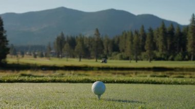 Yeşil sahadaki beyaz golf topu fotokopi uzayı ile aydınlık bir günde bulanık golf sahasında çekilecek. Spor, eğlence sektörü. Golf topu ve golf sopası yeşil çimlerin üzerinde.
