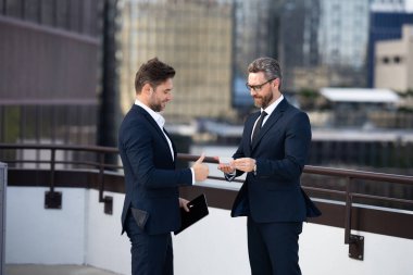 Bir adam ve bir adam kartvizitlerini değiş tokuş ediyorlar. Bir işadamı, bir iş adamına ofis dışında kartvizitini verir. Kredi kartı tutan takım elbiseli bir adam.