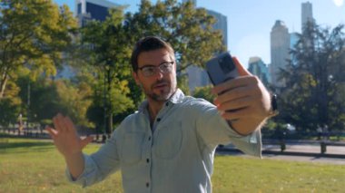 New York, Manhattan 'daki Central Park' ta selfie çeken şık bir adam. Parkta görüntülü telefon görüşmesi. Mutlu genç adam selfie çekiyor ve barış jesti yapıyor Times Meydanı, New York City, ABD.