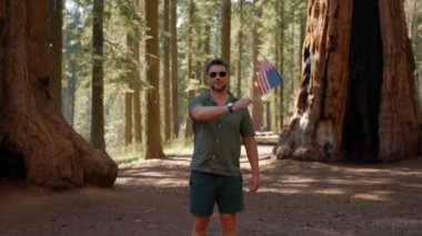 Açık havada Amerikan bayrağı. Ormanda mavi bulutlu gökyüzüne karşı ulusal bayrak taşıyan bir adam. 4 Temmuz Bağımsızlık Günü. Anma ve Gaziler Günü. ABD 'nin ulusal bayrağı.