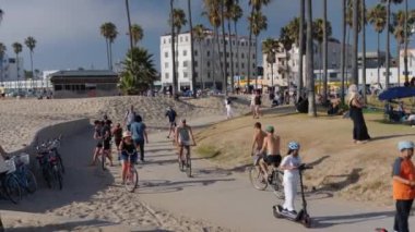 Adamın biri Los Angeles 'taki Roller Coaster Santa Monica plajında kayıyor. Heyecanlı kadınlar parkta paten kayarken el ele tutuşuyorlar. 15 Ağustos 2024 'te, Venedik plajında paten kayarken.