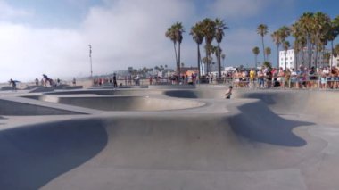 Adamın biri Los Angeles 'taki Roller Coaster Santa Monica plajında kayıyor. Heyecanlı kadınlar parkta paten kayarken el ele tutuşuyorlar. 15 Ağustos 2024 'te, Venedik plajında paten kayarken.