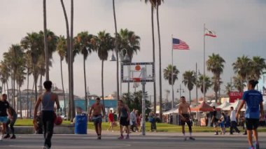 Los Angeles kortunda sokak basketbolcusu. Güneşin doğuşunda basketbol oynuyor. Atletik siyahi adam sahada sırt topu yeteneğini gösteriyor. 25 Eylül 2024 'te sokak basketbolu oynayan arkadaşlar 
