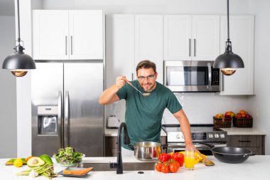 Profesyonel üniformalı modern şef. Kaşıkla tencereye çorba karıştıran erkek aşçının eline yakın plan. Yemek pişirme, aşçılık ve insan konsepti - erkek aşçı tencereli veya tencereli.