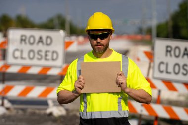 İzinsiz girmek yok. El uzatılmış inşaat işçisi, jest uyarısı yapıyor. İşçinin elinde dur işareti. Tehlikeye karşı uyarıda bulunuyor. Bir mühendis yol çalışması yakınında boş bir reklam panosu tutuyor.