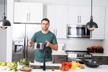 Profesyonel üniformalı modern şef. Kaşıkla tencereye çorba karıştıran erkek aşçının eline yakın plan. Yemek pişirme, aşçılık ve insan konsepti - erkek aşçı tencereli veya tencereli.