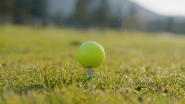 Golf sahasında güneşin doğuşuyla birlikte golf sahası. Yeşil çim tarlasında golf topunu kapat. Golf sopasıyla topa vurmak. Etkin bir eğlence türü. 