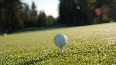 Golf sahasında güneşin doğuşuyla birlikte golf sahası. Yeşil çim tarlasında golf topunu kapat. Golf sopasıyla topa vurmak. Etkin bir eğlence türü. 