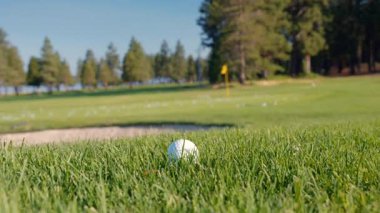 Golf sahasında güneşin doğuşuyla birlikte golf sahası. Yeşil çim tarlasında golf topunu kapat. Golf sopasıyla topa vurmak. Etkin bir eğlence türü. 