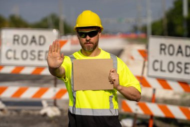 İzinsiz girmek yok. El uzatılmış inşaat işçisi, jest uyarısı yapıyor. İşçinin elinde dur işareti. Tehlikeye karşı uyarıda bulunuyor. Bir mühendis yol çalışması yakınında boş bir reklam panosu tutuyor.