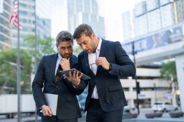 İki yönetici şehirdeki bir tabletten haberleri kontrol ederken şoka girmiş. Takım elbiseli erkek işadamları korku ve stresle tepki verir. Sahne siyaseti, Amerikan ekonomisini, finans ve piyasa çöküşünü vurguluyor.