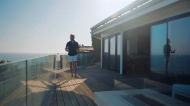 Şık bir adam deniz kıyısında bir bardak şarapla huzurlu bir yürüyüş yapmayı sever. Sahne güven, zenginlik ve duygusal sakinlik yayıyor. Mükemmel gün batımı ışığı biraz lüks katar..