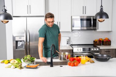 Profesyonel üniformalı modern şef. Kaşıkla tencereye çorba karıştıran erkek aşçının eline yakın plan. Yemek pişirme, aşçılık ve insan konsepti - erkek aşçı tencereli veya tencereli.