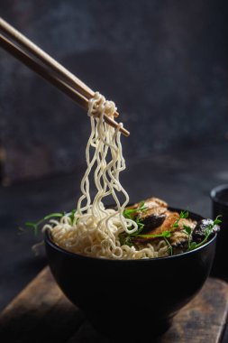 Noodles with eringi mushrooms in a black plate