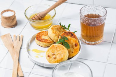 syrniki with honey on a white plate