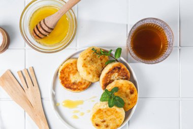 syrniki with honey on a white plate