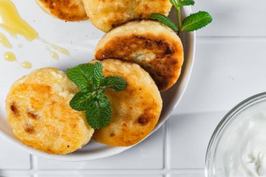 syrniki with honey on a white plate