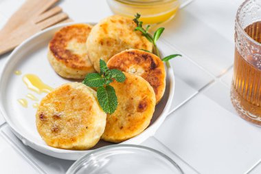 syrniki with honey on a white plate