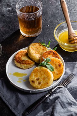 syrniki with honey on a white plate