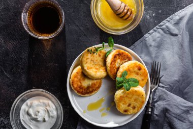 syrniki with honey on a white plate