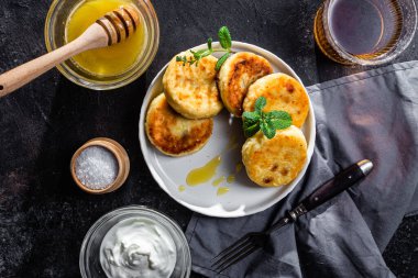 syrniki with honey on a white plate