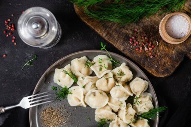 Ekşi kremalı hamur tatlısı ve siyah tabakta otlar. Etli börek.