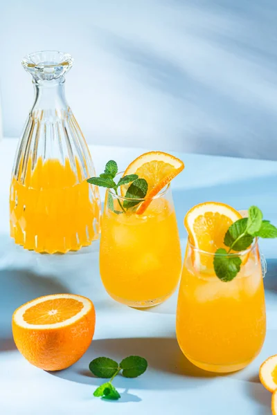 stock image Fresh orange juice with ice in a glass on a blue background. orange cocktail