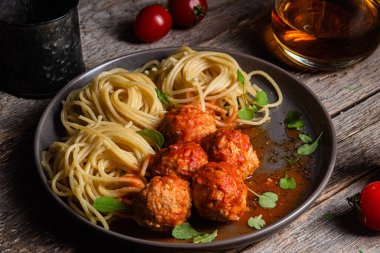 Köfteli makarna ve ahşap bir masada bir tabakta sos.