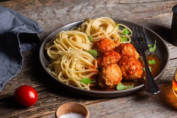 Köfteli makarna ve ahşap bir masada bir tabakta sos.