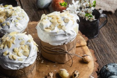 Ahşap arka planda kremalı ve badem yapraklı Paskalya keki.