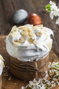 Ahşap arka planda kremalı ve badem yapraklı Paskalya keki.