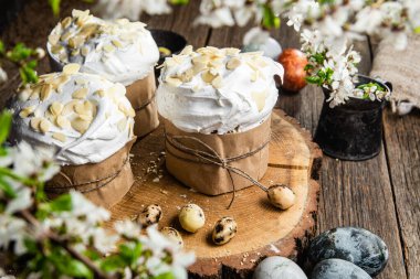 Ahşap arka planda kremalı ve badem yapraklı Paskalya keki.