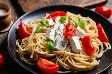 Tabakta peynirli ve domatesli spagetti. İtalyan makarnası