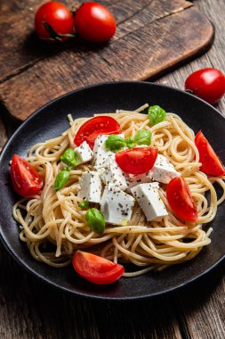 Tabakta peynirli ve domatesli spagetti. İtalyan makarnası