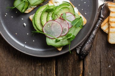 Krem peynirli beyaz ekmek tostu, avokado, salatalık ve turp.