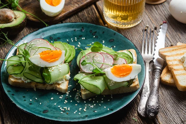 stock image White bread toasts with cream cheese, egg, avocado, cucumber and radish in a plate