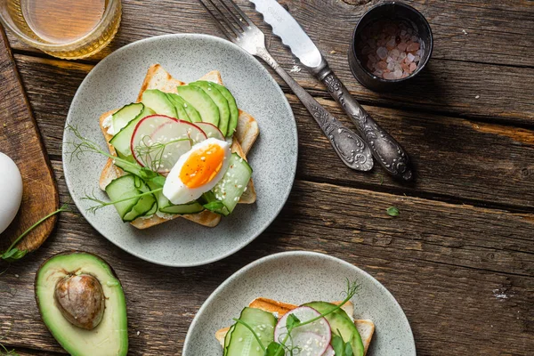 stock image White bread toasts with cream cheese, egg, avocado, cucumber and radish in a plate