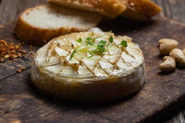 Ahşap bir tahtanın üzerinde fırında peynirli Camembert peyniri. Baget.