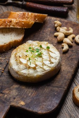 Ahşap bir tahtanın üzerinde fırında peynirli Camembert peyniri. Baget.