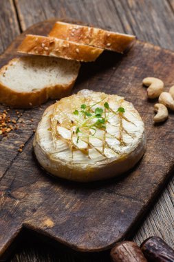 Ahşap bir tahtanın üzerinde fırında peynirli Camembert peyniri. Baget.