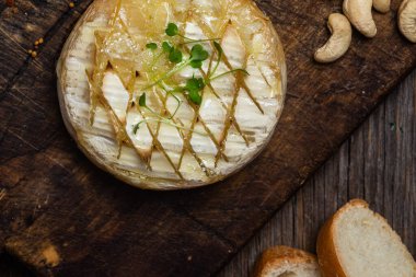 Ahşap bir tahtanın üzerinde fırında peynirli Camembert peyniri. Baget.