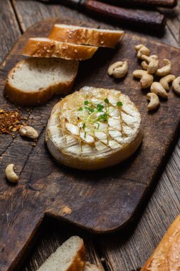 Ahşap bir tahtanın üzerinde fırında peynirli Camembert peyniri. Baget.