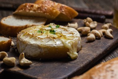 Ahşap bir tahtanın üzerinde fırında peynirli Camembert peyniri. Baget.