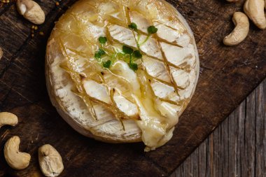 Ahşap bir tahtanın üzerinde fırında peynirli Camembert peyniri. Baget.