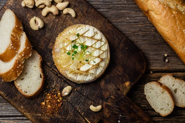 stock image Baked Camembert cheese on a wooden board. Baguette