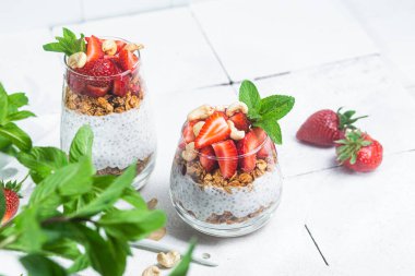 Beyaz arka planda yoğurtlu granola, chia ve çilek.